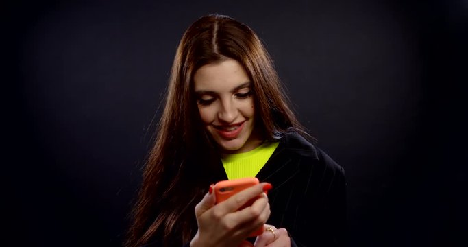 happy girl uses smartphone on black background slow motion