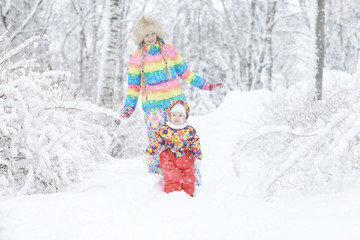 young woman and a young child in a bright colored clothing playing in the winter snow