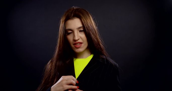 sensual lady unbuttons stylish jacket on black background