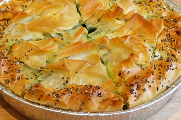 Concetto di cucina greca. Torta Spanakopita fatta in casa. Torta greca con spinaci e feta formaggio sul tavolo di legno.