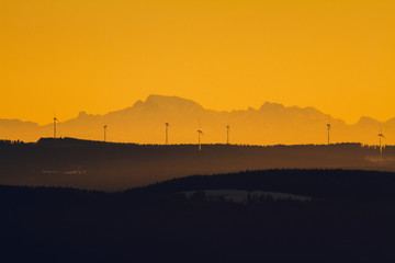 wind towers during sunset with mountains in the background