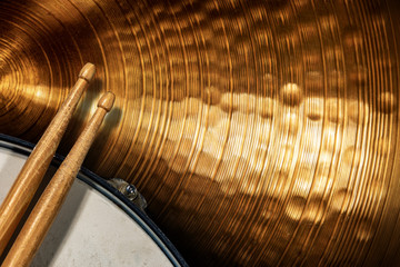 Close-up of two wooden drumsticks on an old metallic snare drum and golden colored cymbal with copy space. Percussion instrument - obrazy, fototapety, plakaty
