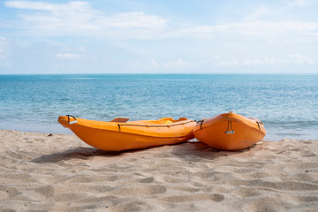 Two colorful orange kayaks on a sandy beach ready for paddlers in sunny day. Several orange...