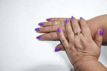 On a white background, well-groomed woman's hands with manicure, nails covered with a violet gel.