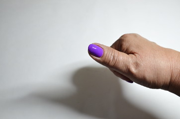 On a white background, well-groomed woman's hands with manicure, nails covered with a violet gel.