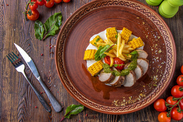 Baked pork served with french fries, corn and pesto, restaurant platter, Horizontal orientation, Closeup
