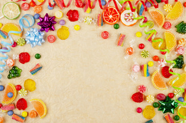 Flat lay view at frame made of different type color and taste candies on gold background. Space for...