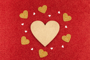 Valentine Day Composition: Gold Wooden Heart with Small Hearts Around on Red Glitter Background. Concept of Love, Birthday, Happy Valentine's Day, Merry Christmas. Top View