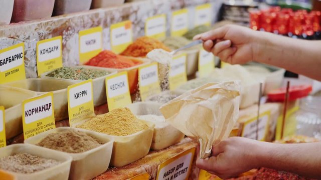seller pours dry ground garlic into bag near store display
