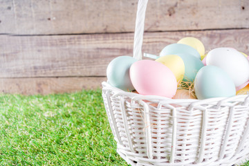 Colorful pastel Easter eggs on green and wooden garden terrace.  Funny spring decoration. Happy Easter greeting card background.