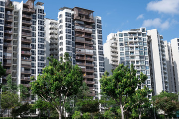 Frontal shot of residential condominium with green trees in front