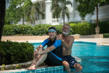 Fototapeta na wymiar Senior Couple Relaxing In Swimming Pool