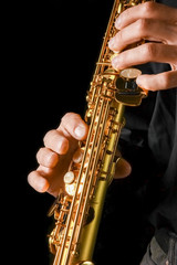 soprano saxophone in hands on a black background