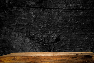 Empty wooden table on a background of dark blurred wall, empty space for product above.