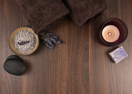 Spa and wellness lavender accessories top view stock images. Spa and wellness setting. Bath salt, brown towels, lava stones, candle, lavender and soap on a wooden background with copy space for text
