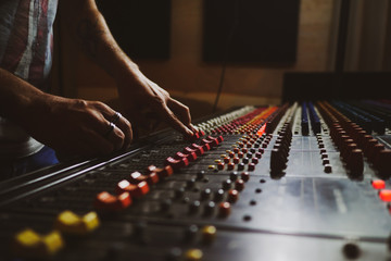 Music producer working in music studio, controlling the sound mixer