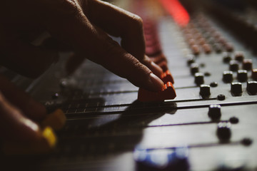 Music producer working in music studio, controlling the sound mixer