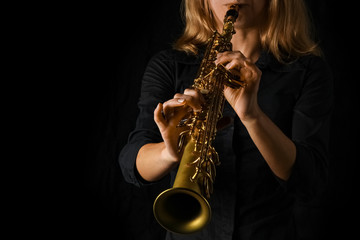 soprano saxophone in hands on a black background