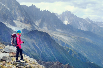 Woman Hiker with backpacks relaxing on top of a mountain and enjoying the view of valley
