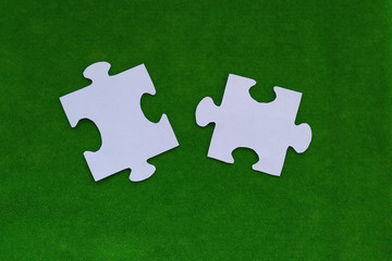 Puzzles made of white paper on a green background.