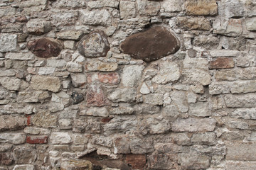 Old wall made of rocks. Medieval surface made of bricks. Texture of an old rocks sticket up with a cement.