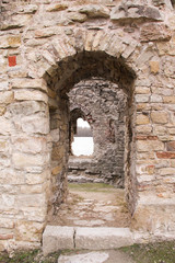 Fototapeta na wymiar Portal in the medieval castle wall. The wall built of rocks and bricks with a window in the middle. 