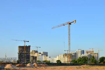 Tower cranes constructing a new building at a construction site. Renovation program, concept of the...