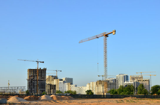 Tower cranes constructing a new building at a construction site. Renovation program, concept of the building industry. Installation of water main, sanitary sewer, storm drain systems in city - Image