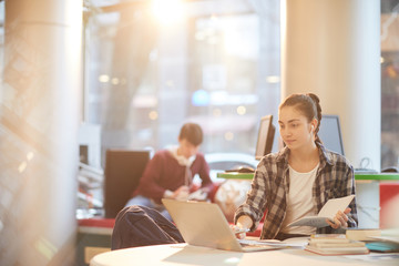 College student working online on laptop computer while sitting at desk in the library