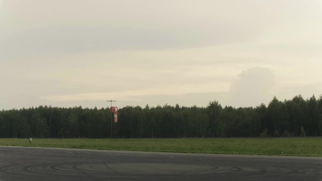 Wide shot of Windsock at airport. Forest in the background