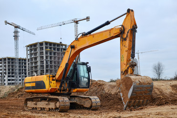Excavator digs ground at a construction site for installing concrete storm pipes. Backhoe the...
