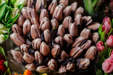 Beautiful bouquet of purple brown tulips with a green leaves in the transparent wrapping paper