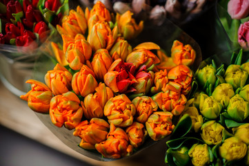Beautiful bouquets of yellow, orange and red tulips with a green leaves in the transparent wrapping paper