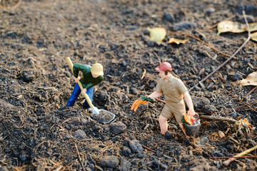 Miniature farmer is digging the soil to plant trees Taking care of preserving the environment and the world by planting trees, selective focus at miniature people               