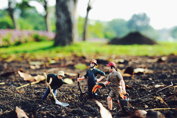 Miniature farmer is digging the soil to plant trees Taking care of preserving the environment and the world by planting trees, selective focus at miniature people               