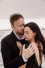Young beautiful wedding couple in black clothes stand on an iceberg on an ice lake in Iceland