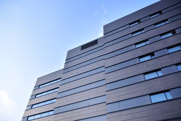 A view at a straight facade of a modern building with a dark grey facade.