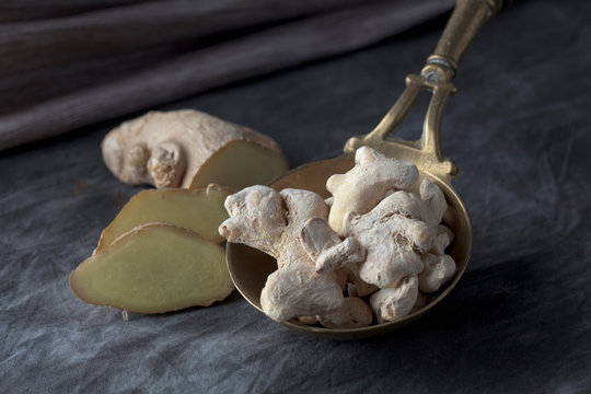Brass spoon with dried ginger on textile, close up