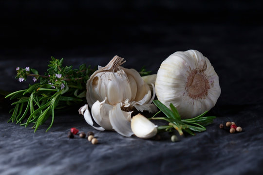 Garlics with herbs, rosemary, thyme and peppercorns on textile, close up