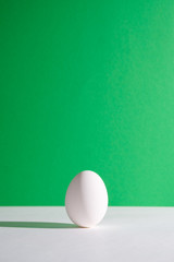 White egg on a green background in the center. Modern easter card. Design, visual art, minimalism