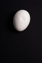Broken eggs top view on black background