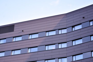 Fototapeta na wymiar A view at a straight facade of a modern building with a dark grey facade.