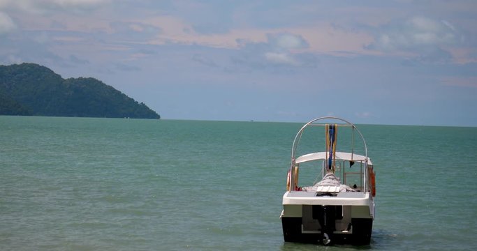 parasailing boat anchored near tropical beach  establishing shot of tropical island in background and boat in foreground