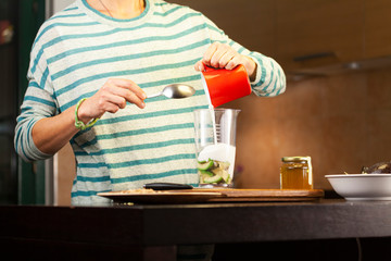 young woman pours yogurt into the cup