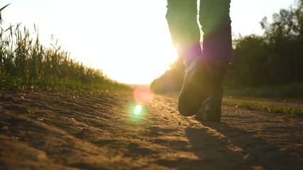 A man farmer goes on a rural road along a green wheat field at sunset. Way to success. Successful way in business. The concept of success and prosperity