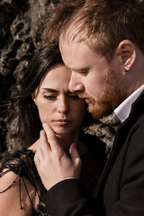 young wedding couple in black clothes stand on lava rock