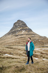 male traveler in green clothes  goes on a background of mountains in Iceland