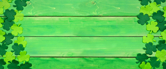 St Patricks Day banner with double side border of shamrocks. Top view over a green wood background....