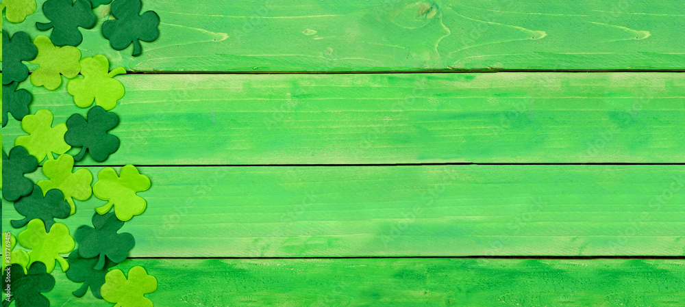 Poster st patricks day banner with side border of shamrocks. top view over a green wood background. copy sp