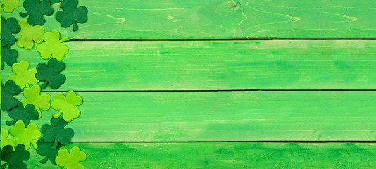 St Patricks Day banner with side border of shamrocks. Top view over a green wood background. Copy...